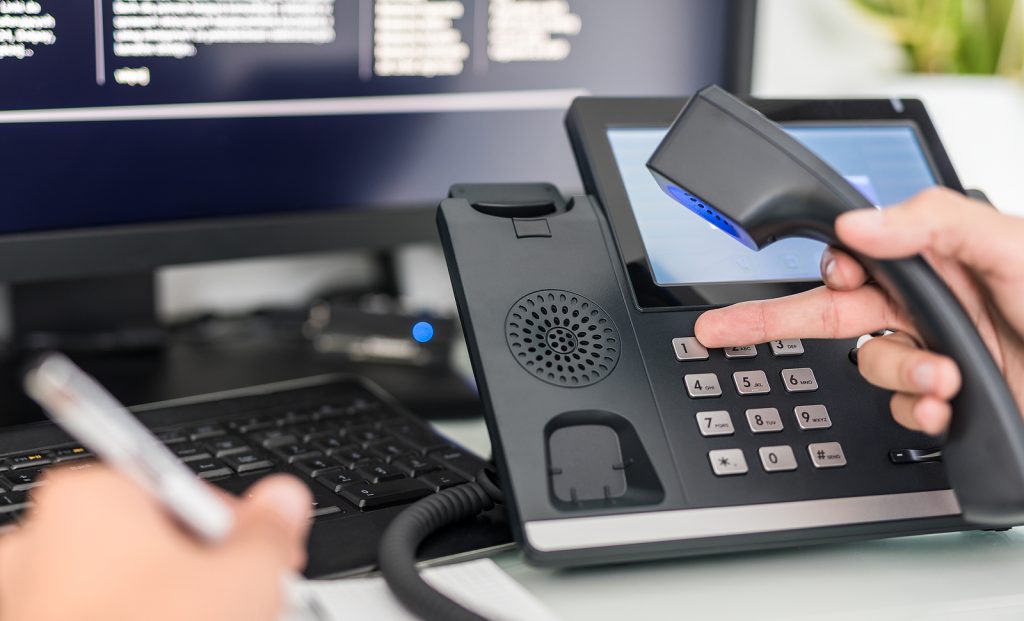 A business desk phone and laptop on a desk